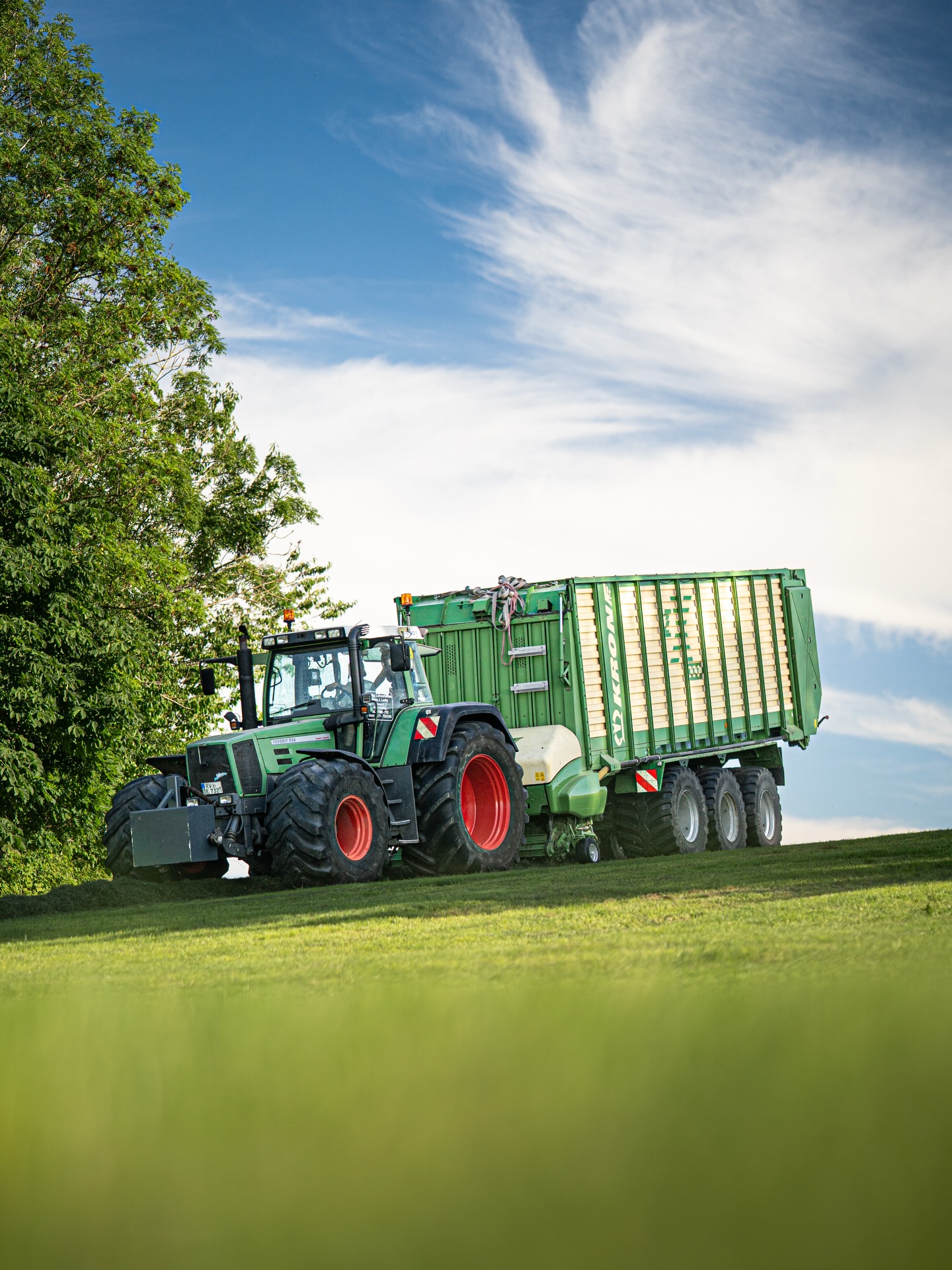 Traktor mit Ladewagen auf grüner Anhöhe